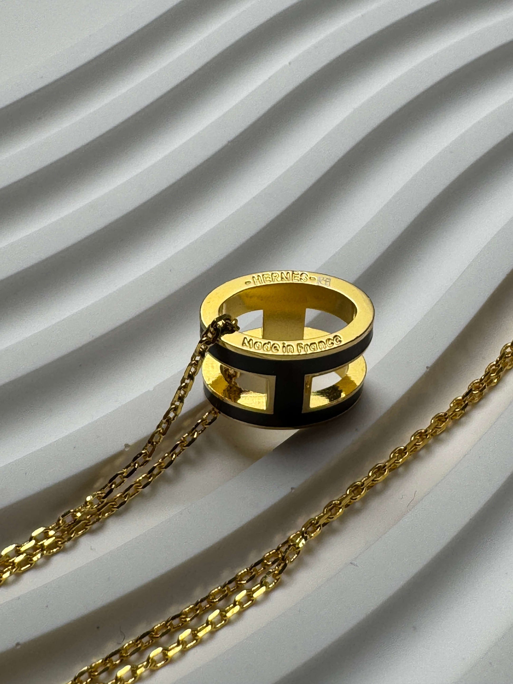 Yellow gold enamel H pendant necklace on display bust